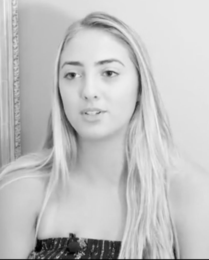 woman with long hair and microphone on her shirt