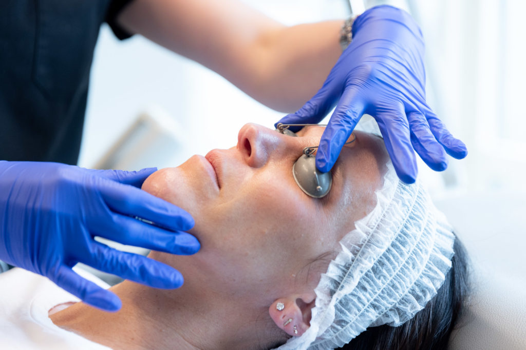 person in gloves placing protective goggles on patient