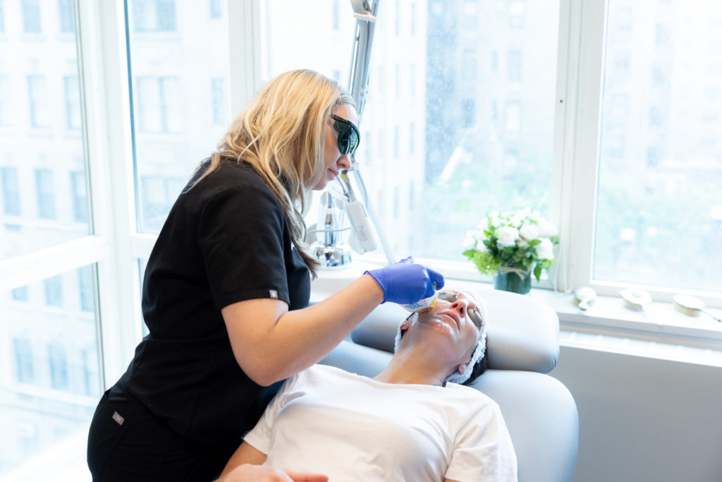 woman in scrubs using BBL machine on young woman