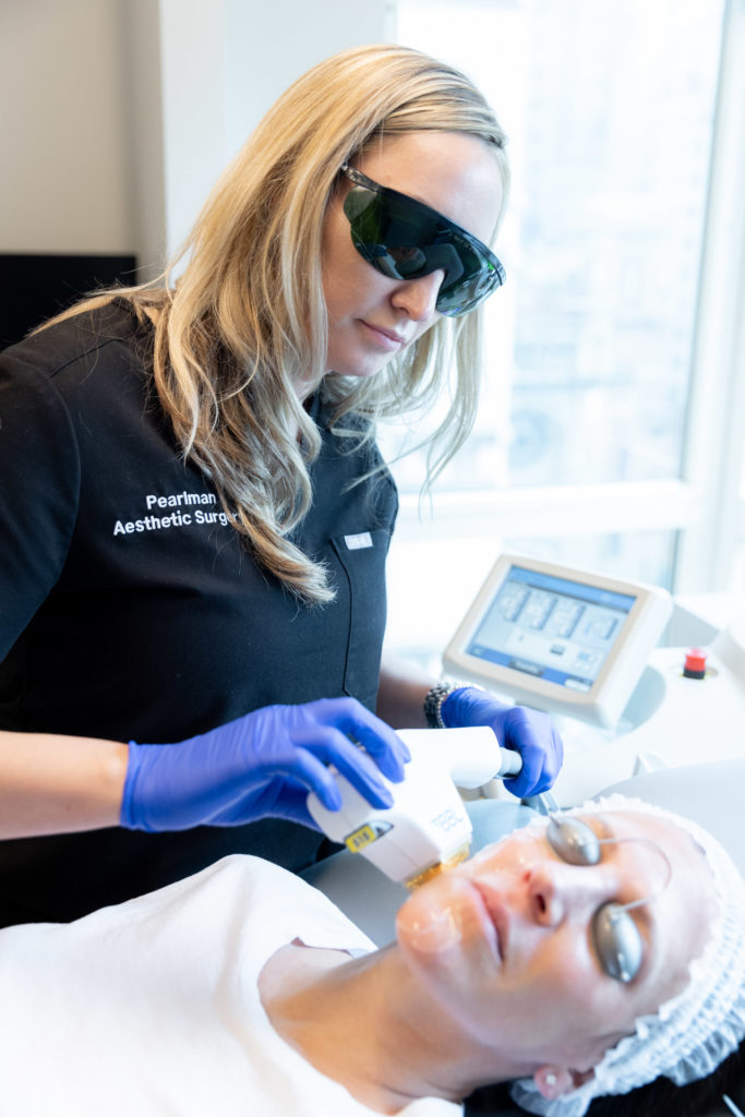 woman in scrubs using BBL machine on young woman