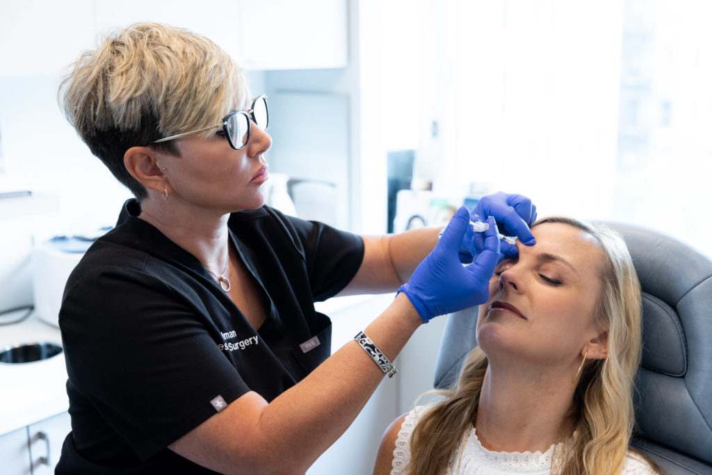 woman in scrubs injecting patient's forehead with Botox