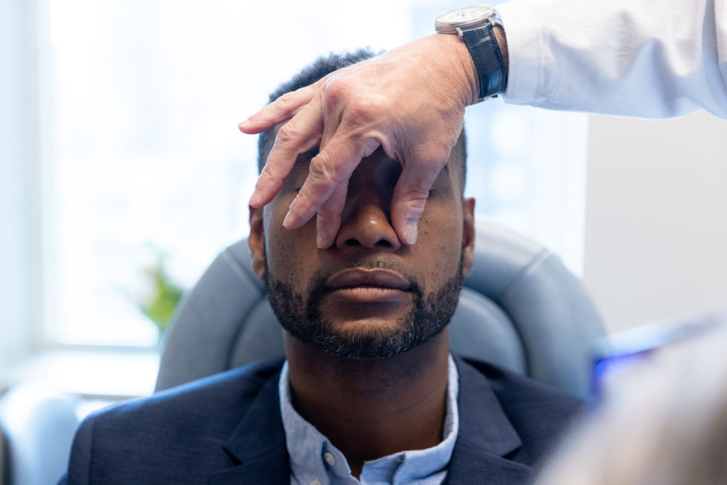 Dr. Pearlman touching a male rhinoplasty patient's nose during consultation