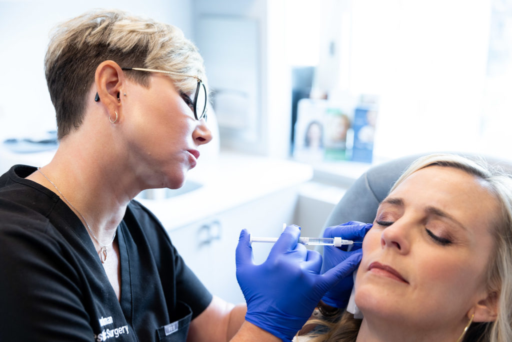 Specialists with gloves injecting filler into patient's face