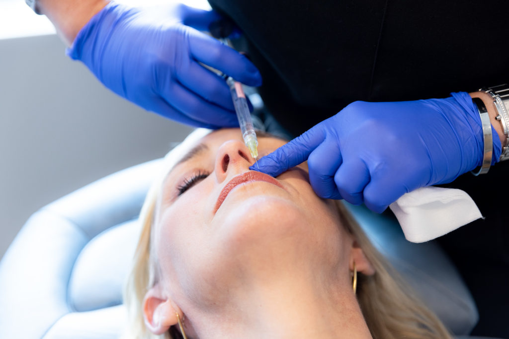 specialist in gloves injecting woman's lips