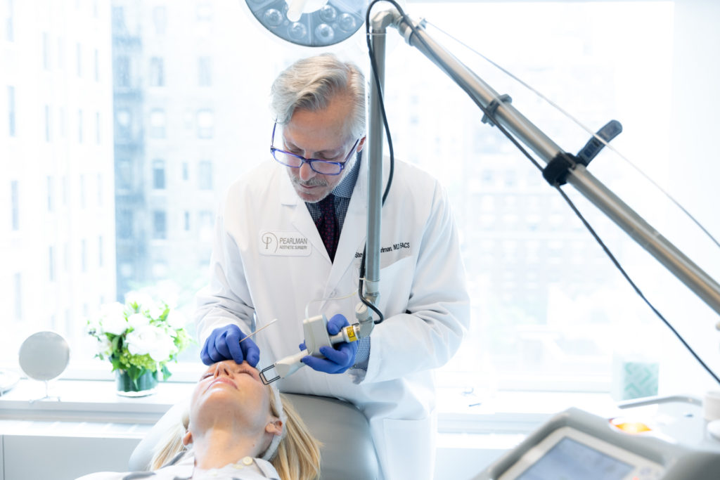 Dr. Pearlman using laser on patient's face