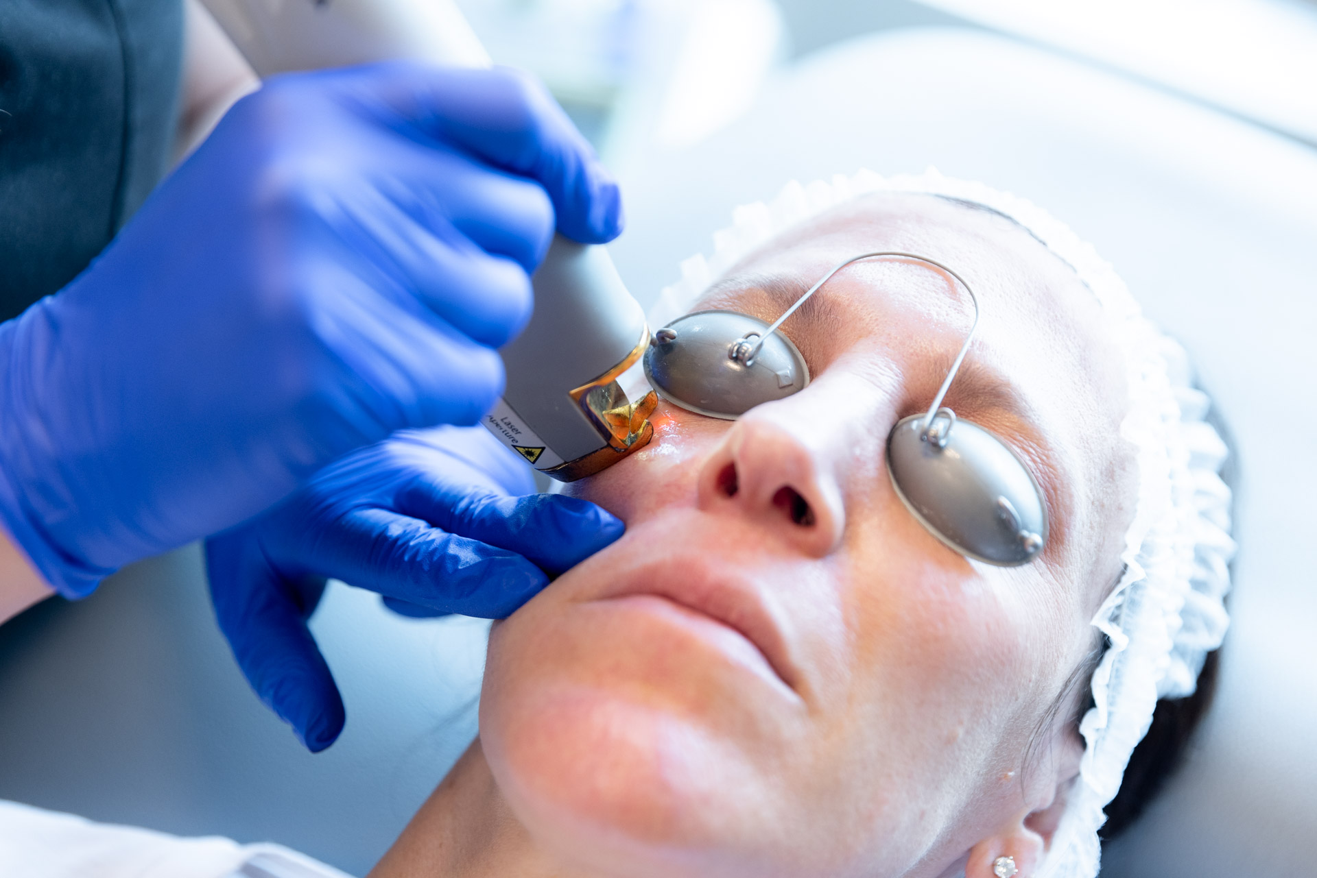 Specialist in gloves performing laser vein treatment on patient