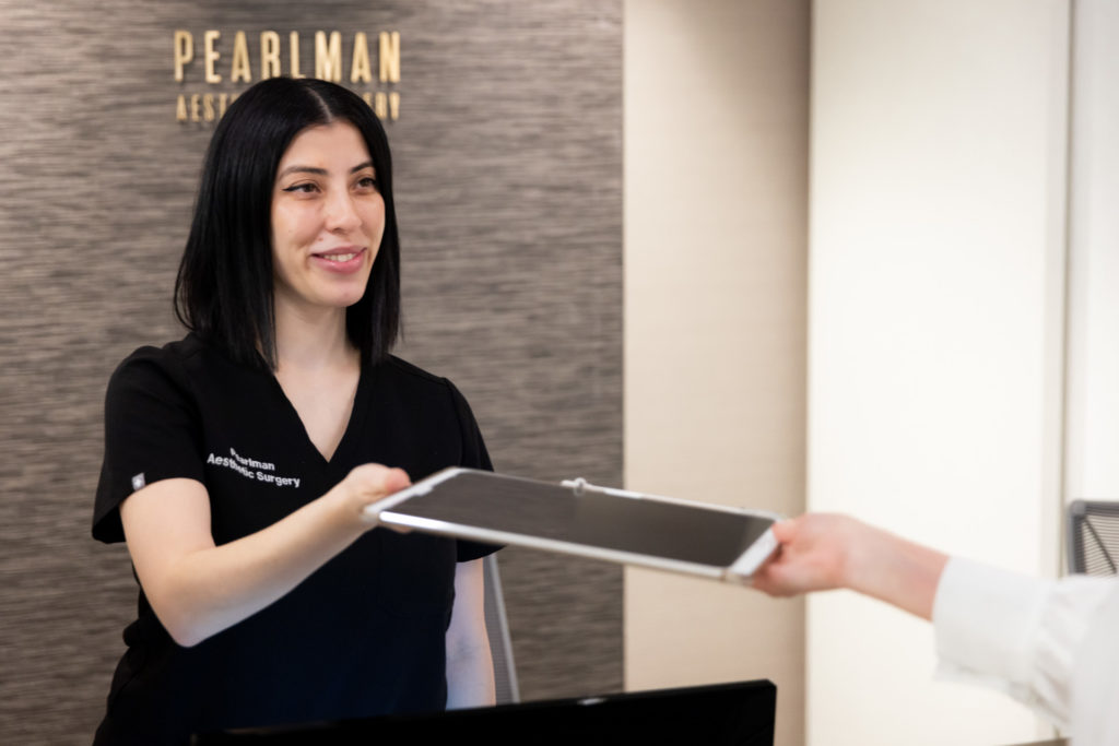 front desk worker smiling giving patient a tablet