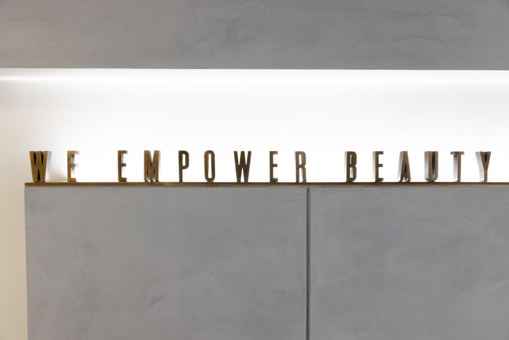 Pearlman gold sign that says we power beauty