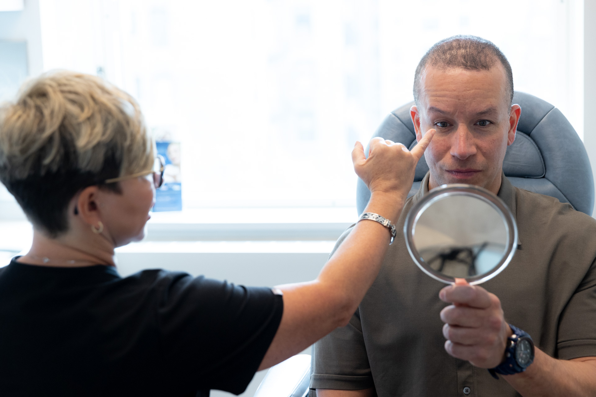 Specialists posting at patient's eye with mirror