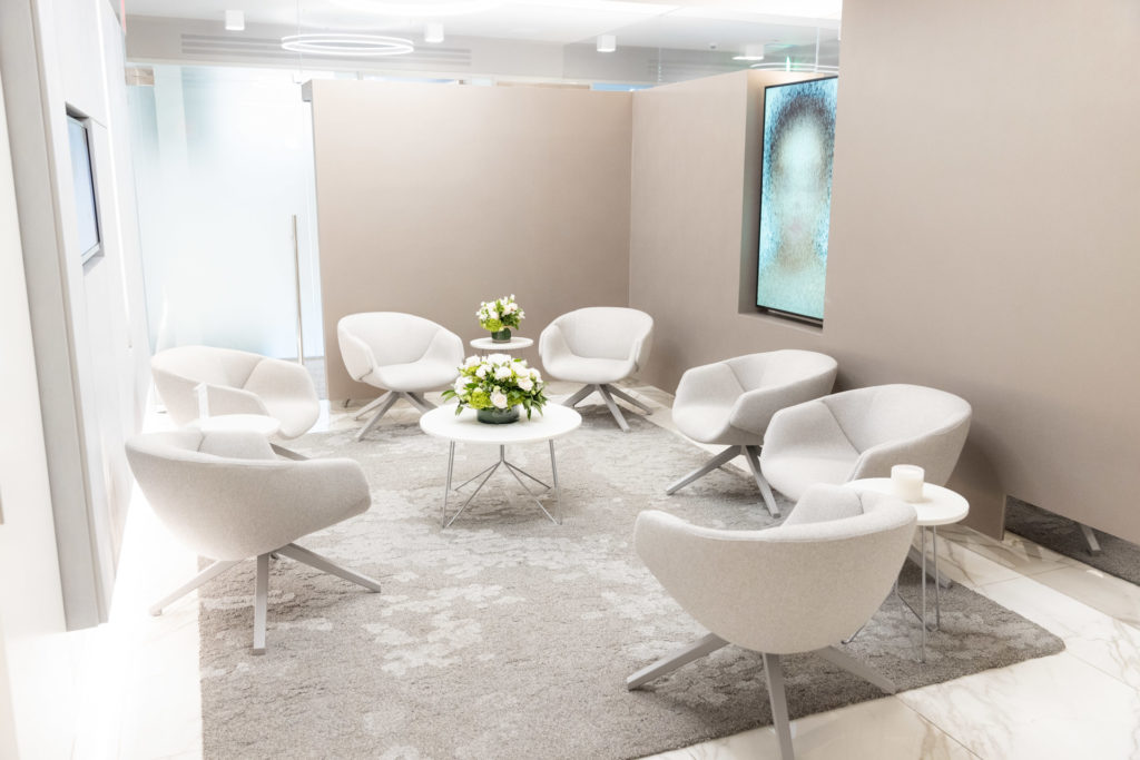 room with empty white chairs and flowers