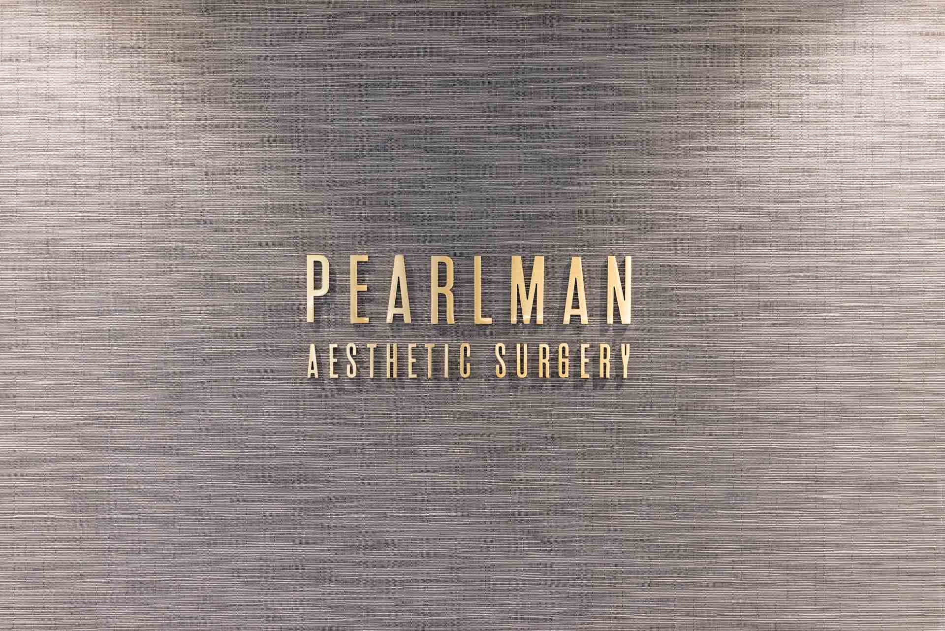 Pearlman Aesthetic Surgery gold sign on gray wall
