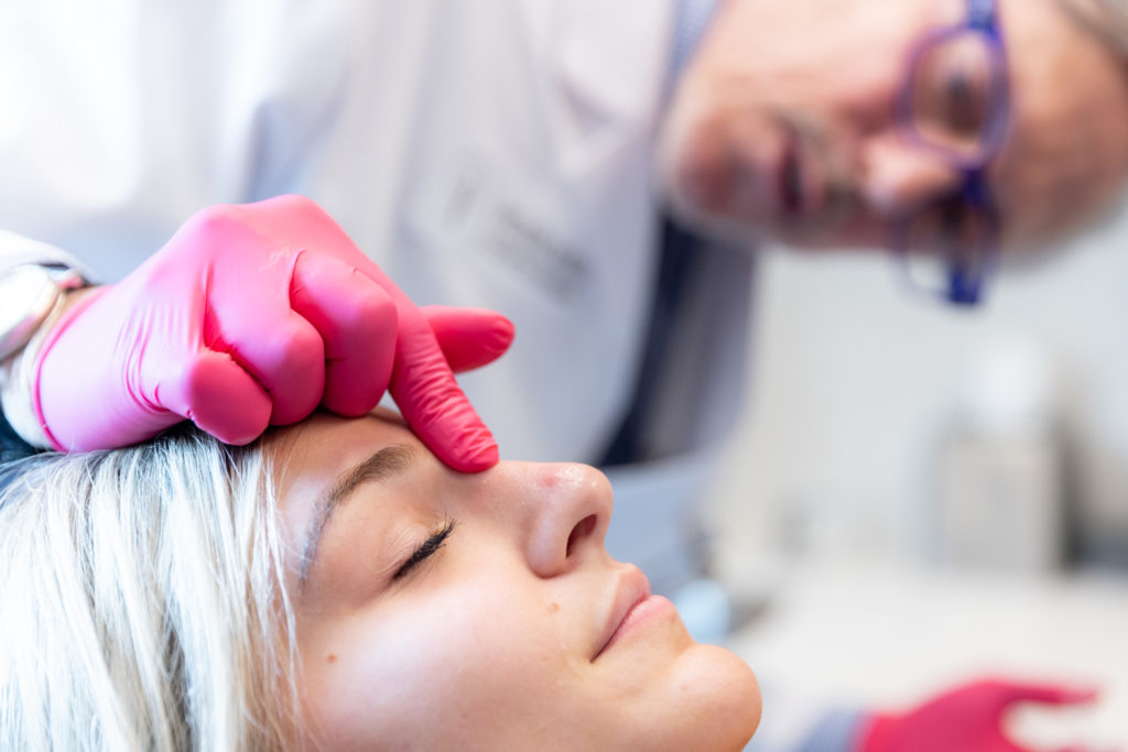 performing nonsurgical rhinoplasty on patient
