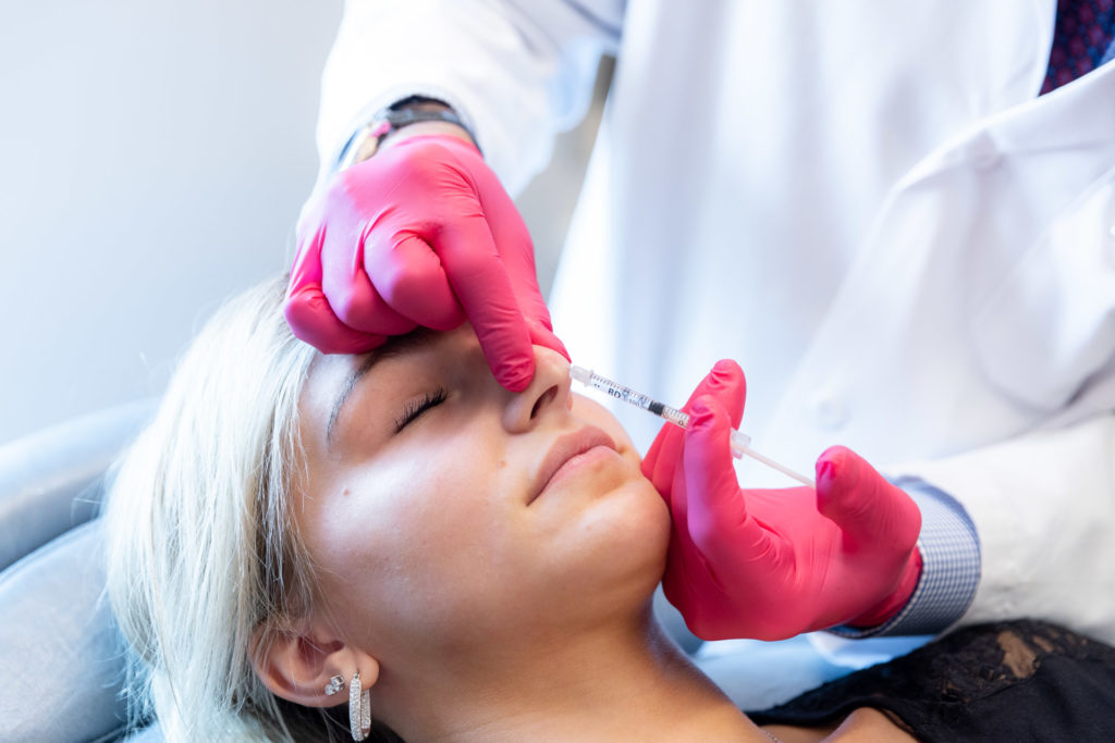 performing nonsurgical rhinoplasty on patient