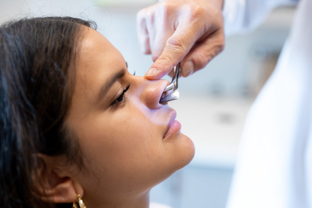 Dr. Pearlman looking at patient's nose during rhinoplasty consultation