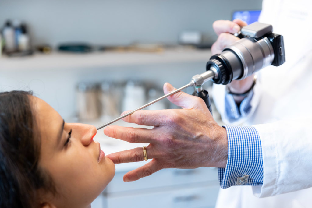 Dr. Pearlman looking at patient's nose with tool during rhinoplasty consultation