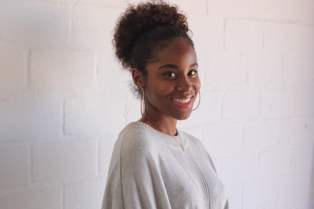 beautiful woman with hoop earrings smiling in front of white wall