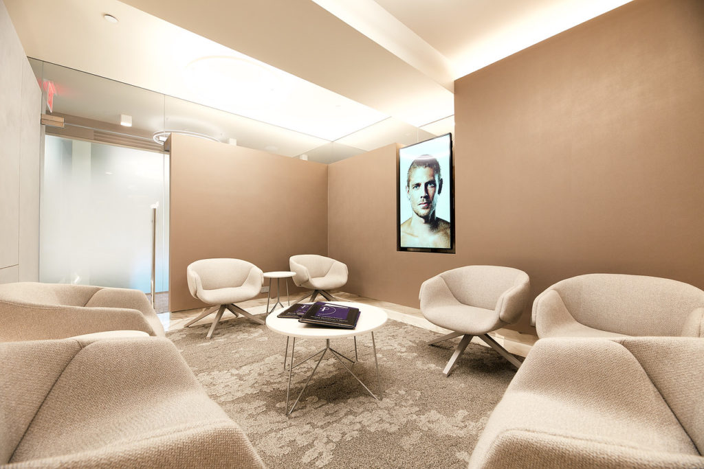 empty chairs in a clean lobby with image of man on TV