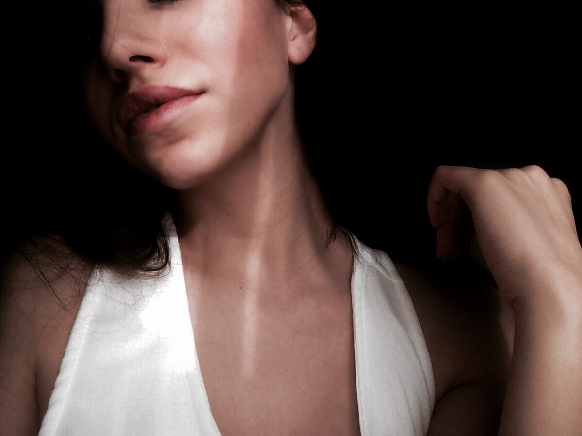 woman touching hair with shadows on her face and neck